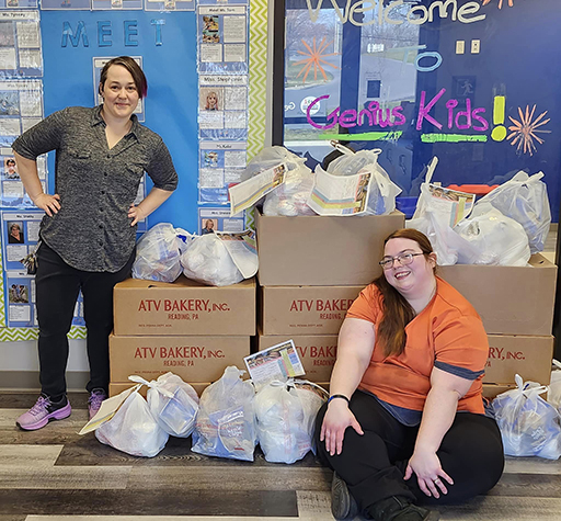 Two women posing with ATV Bakery boxes in a classroom for Tasty Choices Fundraising